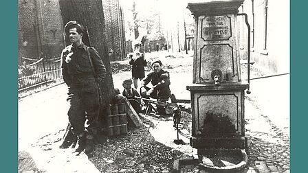 Twee Canadese militairen bij de waterpomp naast de Grote Kerk in Barneveld, april 1945