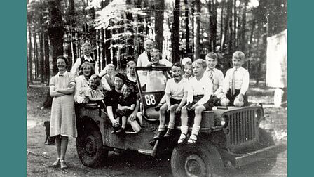 Een Canadese legerjeep met kinderen in het Schaffelaarsebos, april 1945