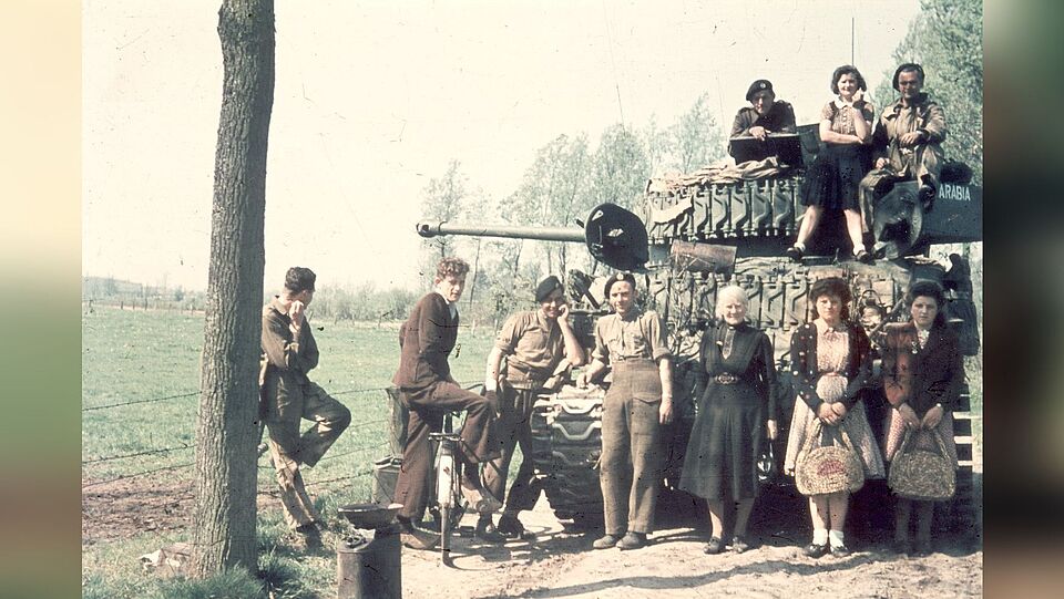 Afbeelding van een Canadese tank aan de Donkervoorterweg, met lokale bewoners en Canadese soldaten.