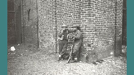 Twee Canadese soldaten leunen tegen de Grote Kerk, 17 april 1945