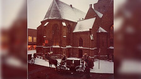 De Grote Kerk in Barneveld in de sneeuw, op de voorgrond een koets met een paard ervoor. 1977